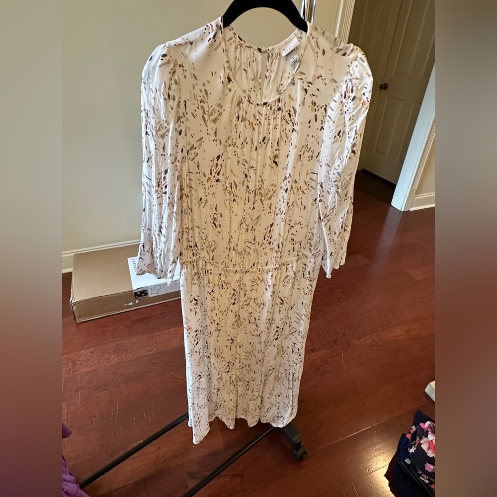 Long sleeve white dress with neutral color pattern.